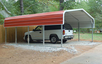 A popular rounded roof style red carport installed on gravel with room for SUV parking.